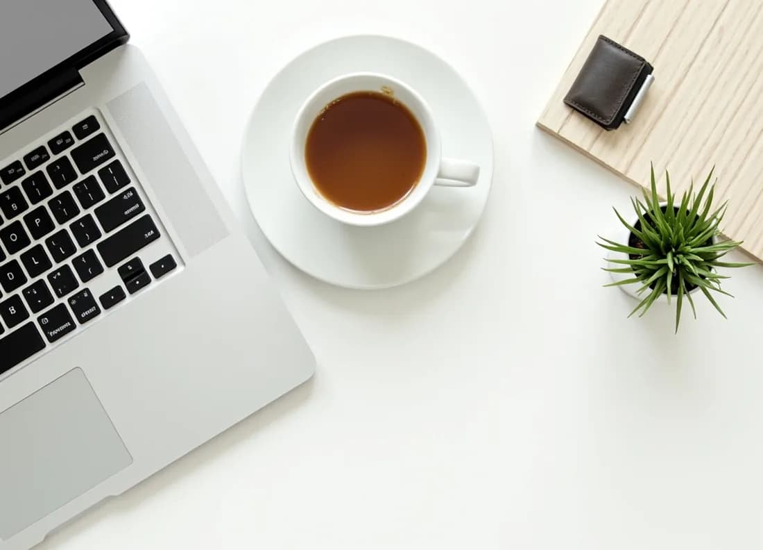 A tidy desk with a laptop, a cup of coffee and a small plant.